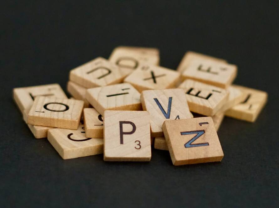 Wooden scrabble tiles in a pile on a black background